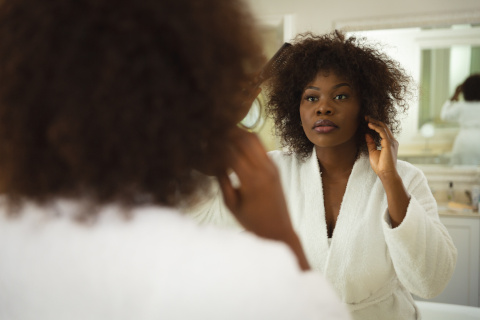 Woman confidently styling her hair in a stylish walk-in shower room in Hampshrie and West Sussex, designed for both accessibility and comfort.